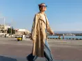 Una chica con estilo, con un look clean girl, pasea por el puerto con un abrigo beige y vaqueros anchos.