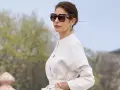 Mujer con gafas de sol grandes y traje blanco, luciendo un estilo casual chic.