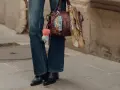 Botas negras elegantes con tacón, perfectas para complementar unos pantalones vaqueros anchos y un bolso de cuero con adornos.