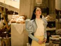 Mujer con estilo coquette aesthetic, con chaqueta celeste de volantes y blusa blanca, en un mercado con pan.