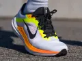 Zapatillas Nike Winflo 10 blancas con detalles en naranja y neón, listas para correr.