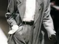Un elegante power suit de espiga gris con camisa a rayas y cinturón negro.