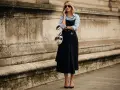 Mujer con un elegante vestido negro sobre una camisa blanca, hablando por teléfono.