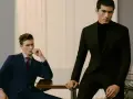 Dos hombres con trajes elegantes, uno azul y otro negro, demuestran el estilo business casual en una oficina moderna.