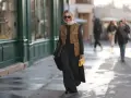 Mujer con chaleco negro corto, falda larga negra y bolso amarillo.
