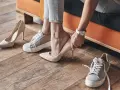 Persona se prueba unos tacones beige, rodeada de varios pares de zapatos. Se aprecian diferentes partes de un zapato, como la suela y el tacón.