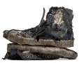 Un par de zapatillas gastadas, rotas y sucias, apiladas una sobre otra. Parecen haber vivido muchas aventuras.
