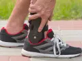 Persona ajustando un soporte para el tobillo dentro de un zapato deportivo, ideal para saber qué zapatos usar después de una fractura de tobillo.