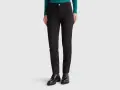 Mujer con pantalones chinos negros y botines gruesos. Un look moderno y versátil.