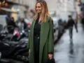 Mujer con traje negro y un abrigo verde olivo, ideal para saber qué abrigo llevar con traje mujer.