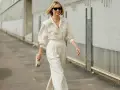 Mujer con un elegante outfit oficina verano: pantalón ancho blanco, camisa holgada y bolso de mano.