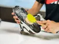Limpiando la suela de goma negra de un zapato con un cepillo y espuma.