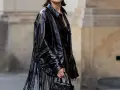 Mujer con vestido negro y chaqueta de charol con flecos. Un look audaz para combinar vestido negro con chaqueta.