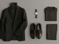 Conjunto elegante: traje negro, jersey de cuello alto, pantalones, reloj y mocasines marrones.