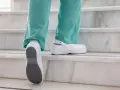 Persona subiendo escaleras con zapatos blancos, mostrando la suela antideslizante. El poliuretano en zapatos ofrece comodidad y durabilidad.
