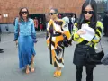 Tres mujeres posan con atuendos de moda. La del centro lleva un vestido estampado y sandalias naranjas, un ejemplo de que son mules.