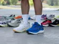 Un corredor muestra varias zapatillas deportivas, buscando el mejor calzado para tendinitis aquiles.