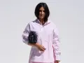 Mujer con una camisa rosa a rayas y un bolso negro.