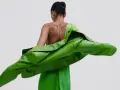 Mujer con un vestido verde brillante y una chaqueta verde vibrante. Un look audaz para combinar vestido verde con chaqueta.