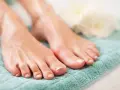 Pies cuidados con esmalte claro sobre toalla turquesa. El pedicura significado es cuidado y belleza para tus pies.