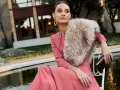 Elegante outfit fiesta invierno: vestido rosa palo, chal de pelo y bolso de mano.