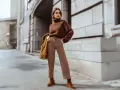 Mujer con suéter marrón y pantalones a rayas, luciendo un impecable estilo monocromático en la calle.