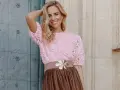 Mujer sonriente con top rosa de encaje y falda marrón, ideal para una boda en octubre, manga corta o larga.