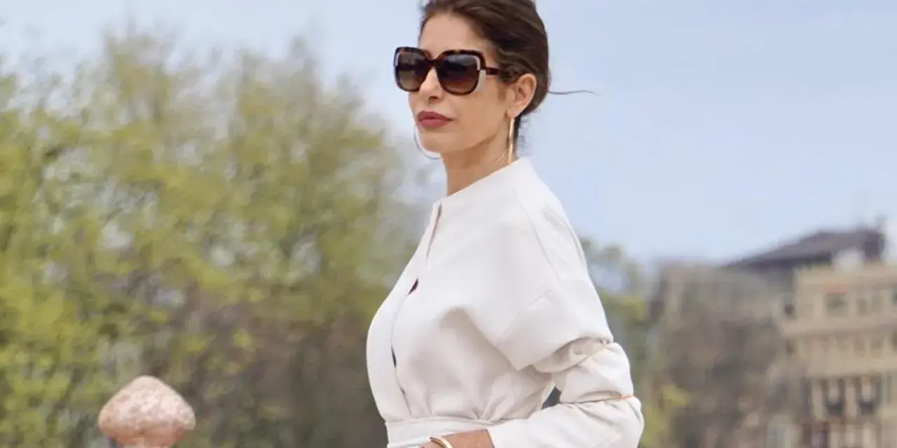Mujer con gafas de sol grandes y traje blanco, luciendo un estilo casual chic.