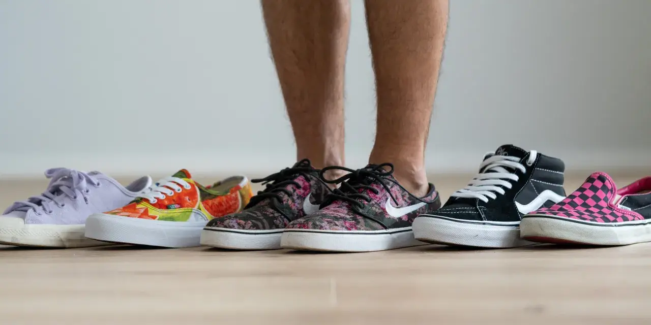 Un hombre elige entre varias zapatillas de **material canvas**. Hay modelos de colores, estampados florales, de cuadros y lisos.