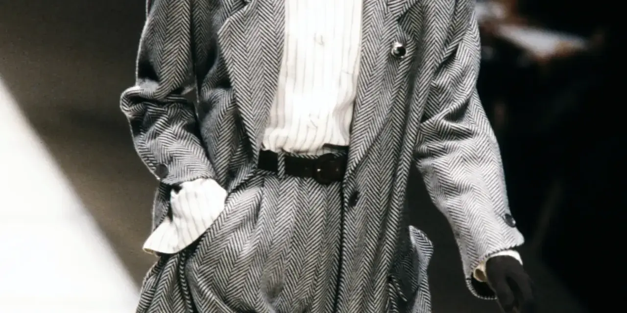 Un elegante power suit de espiga gris con camisa a rayas y cinturón negro.