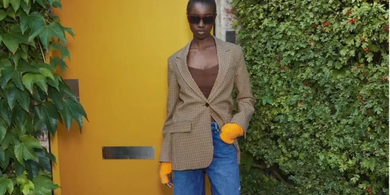 Mujer con blazer de cuadros, top marrón y vaqueros rotos. Ideas de qué ponerse debajo de una blazer para un look moderno.