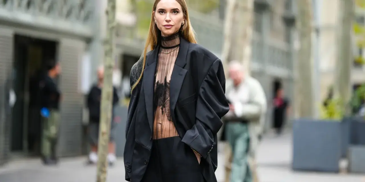 Mujer con traje negro y top transparente, ideal para saber como ir vestida a un cóctel de tarde.