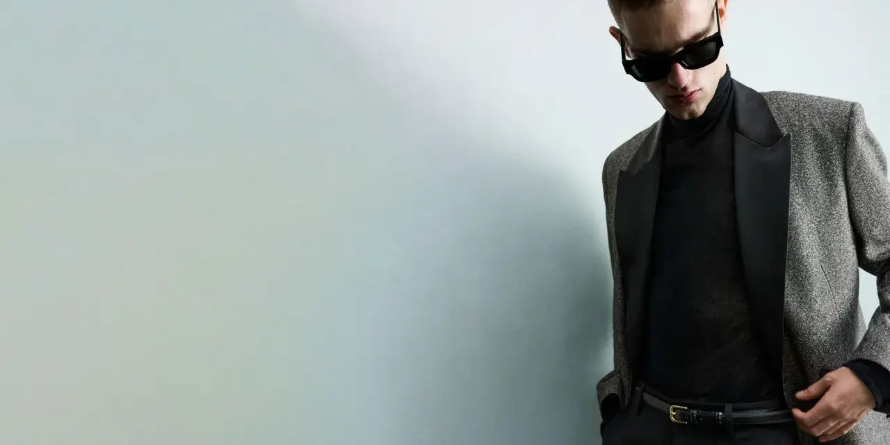 Joven con gafas de sol y traje elegante, listo para una **nochevieja en casa** con estilo.