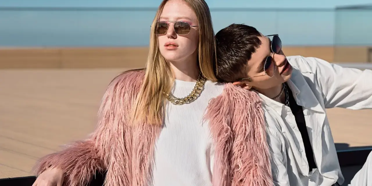 Chica con abrigo rosa peludo y collar dorado, apoyada en un chico con camisa blanca. Inspiración para como ser una chica aesthetic.