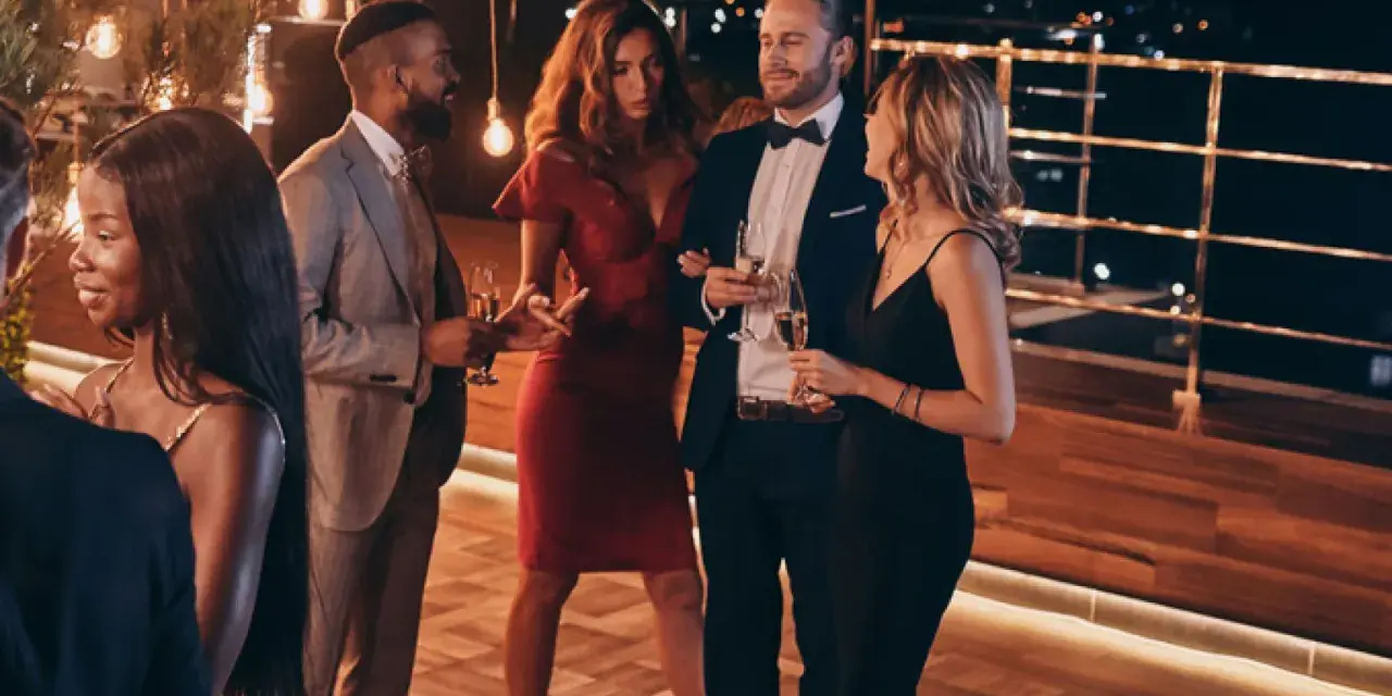 Elegante fiesta en España, cumpliendo el dress code cocktail. Hombres con traje y pajarita, mujeres con vestidos de cóctel.