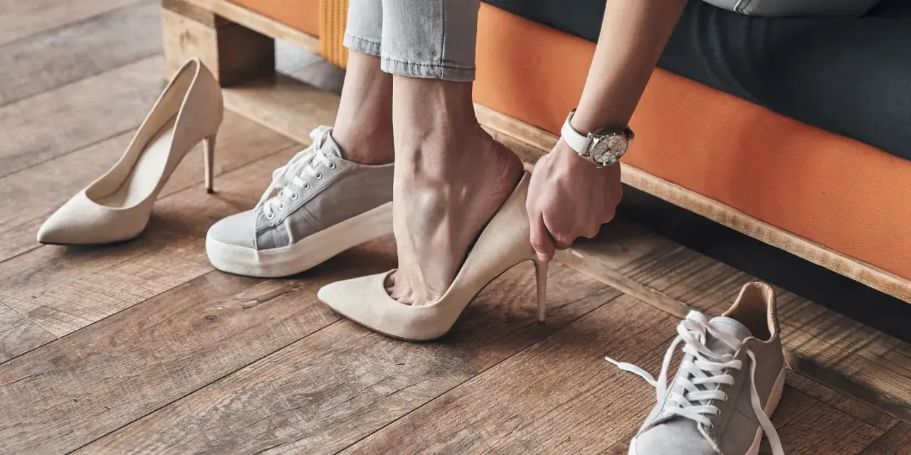 Persona se prueba unos tacones beige, rodeada de varios pares de zapatos. Se aprecian diferentes partes de un zapato, como la suela y el tacón.