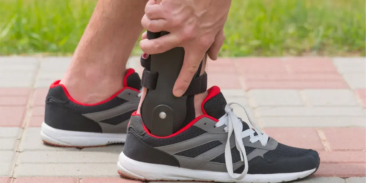 Persona ajustando un soporte para el tobillo dentro de un zapato deportivo, ideal para saber qué zapatos usar después de una fractura de tobillo.