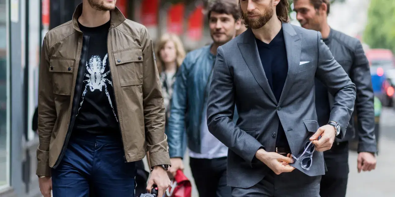 Hombres con estilo, uno con chaqueta y camiseta estampada, otro con traje gris. Dress code casual.