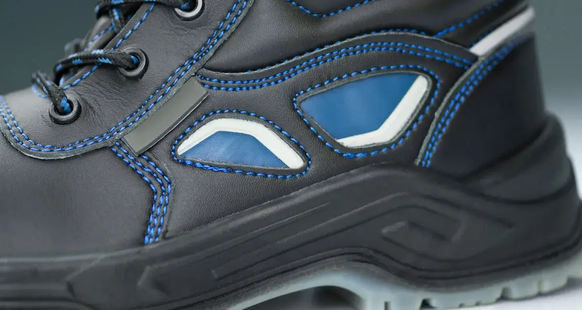 Bota de trabajo negra con costuras azules y detalles en azul y blanco. La suela tpu ofrece agarre y durabilidad para cualquier terreno.