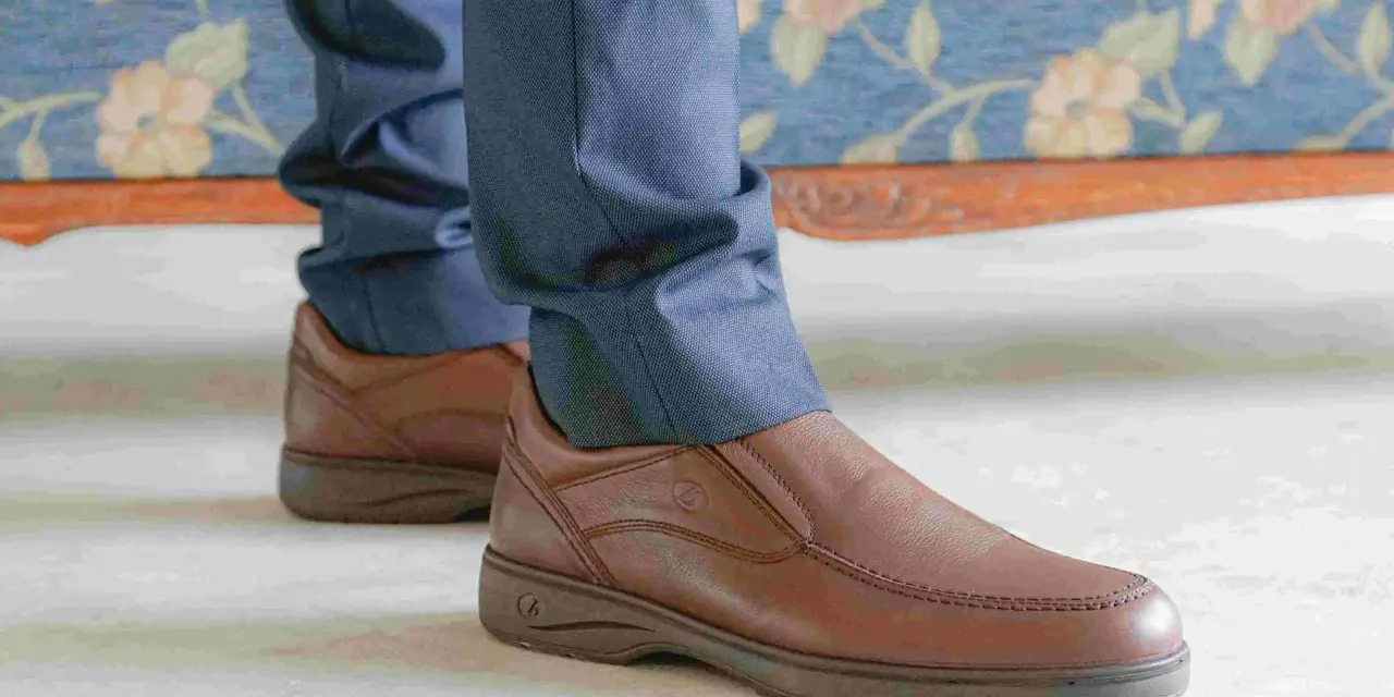 Un hombre viste pantalones azules y unos cómodos mocasines marrones, perfectos para cualquier ocasión.
