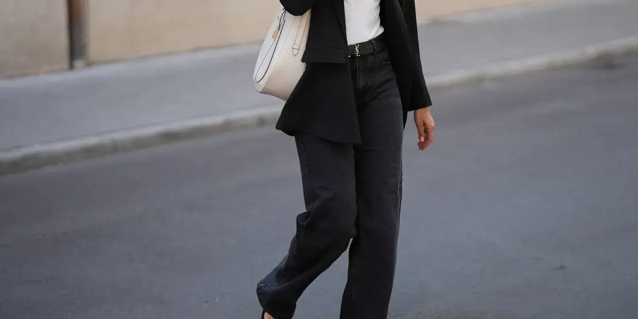 Look con blazer negro y jeans grises anchos. Bolso blanco y sandalias negras completan el atuendo.