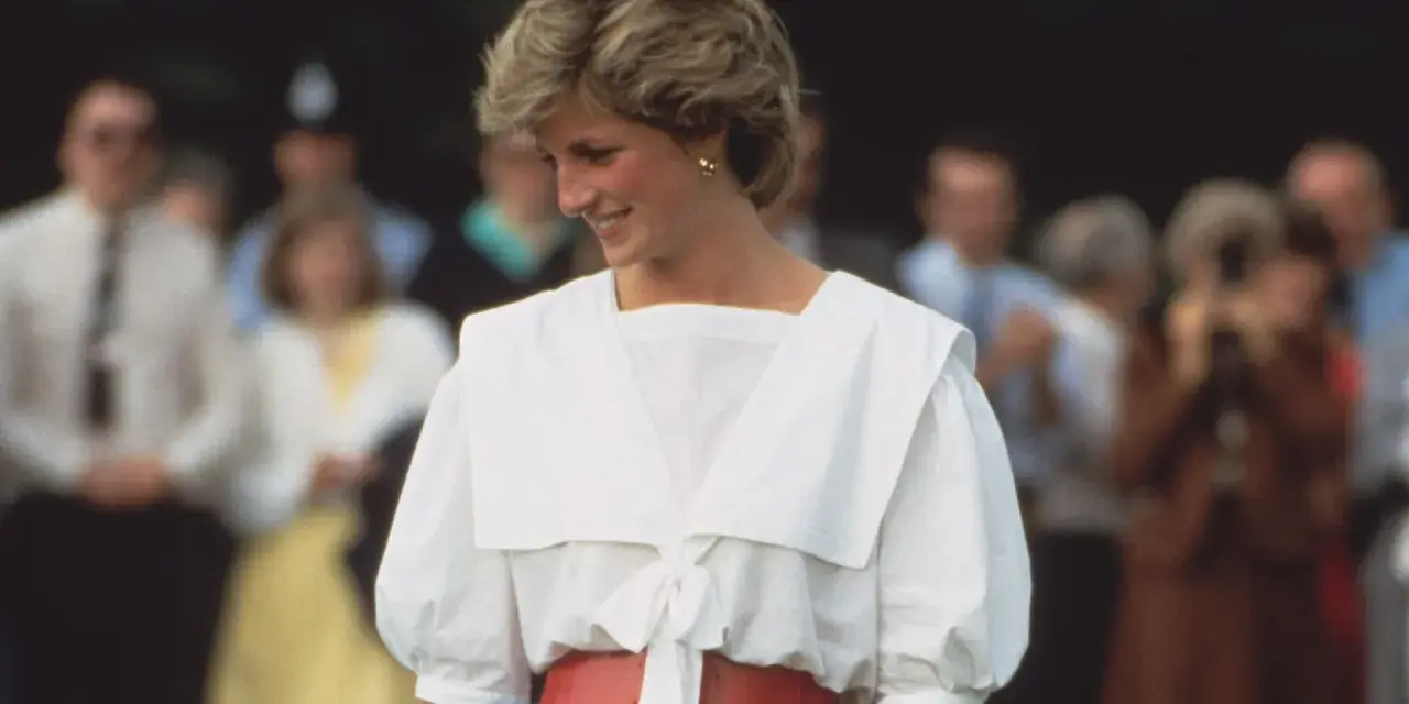 Lady Di sonríe con un conjunto blanco y rojo, un ejemplo de sus icónicos outfits.