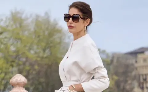 Mujer con gafas de sol grandes y traje blanco, luciendo un estilo casual chic.
