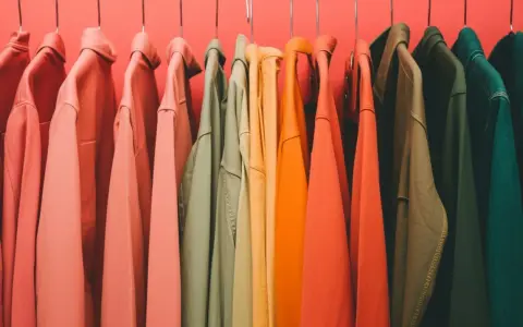 Percheros con ropa de tonos cálidos y fríos, un arcoíris de color verano listo para usar.