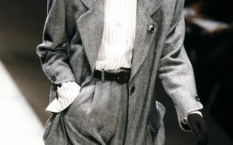 Un elegante power suit de espiga gris con camisa a rayas y cinturón negro.