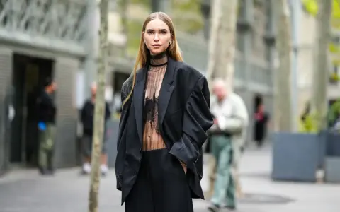 Mujer con traje negro y top transparente, ideal para saber como ir vestida a un cóctel de tarde.