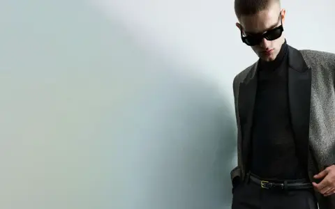 Joven con gafas de sol y traje elegante, listo para una **nochevieja en casa** con estilo.