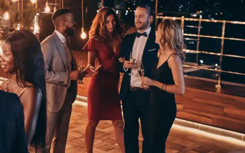 Elegante fiesta en España, cumpliendo el dress code cocktail. Hombres con traje y pajarita, mujeres con vestidos de cóctel.
