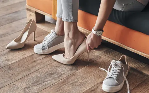 Persona se prueba unos tacones beige, rodeada de varios pares de zapatos. Se aprecian diferentes partes de un zapato, como la suela y el tacón.