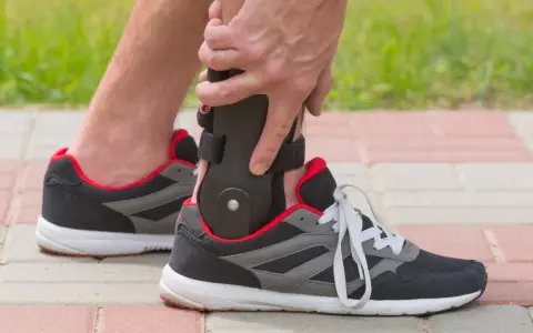 Persona ajustando un soporte para el tobillo dentro de un zapato deportivo, ideal para saber qué zapatos usar después de una fractura de tobillo.